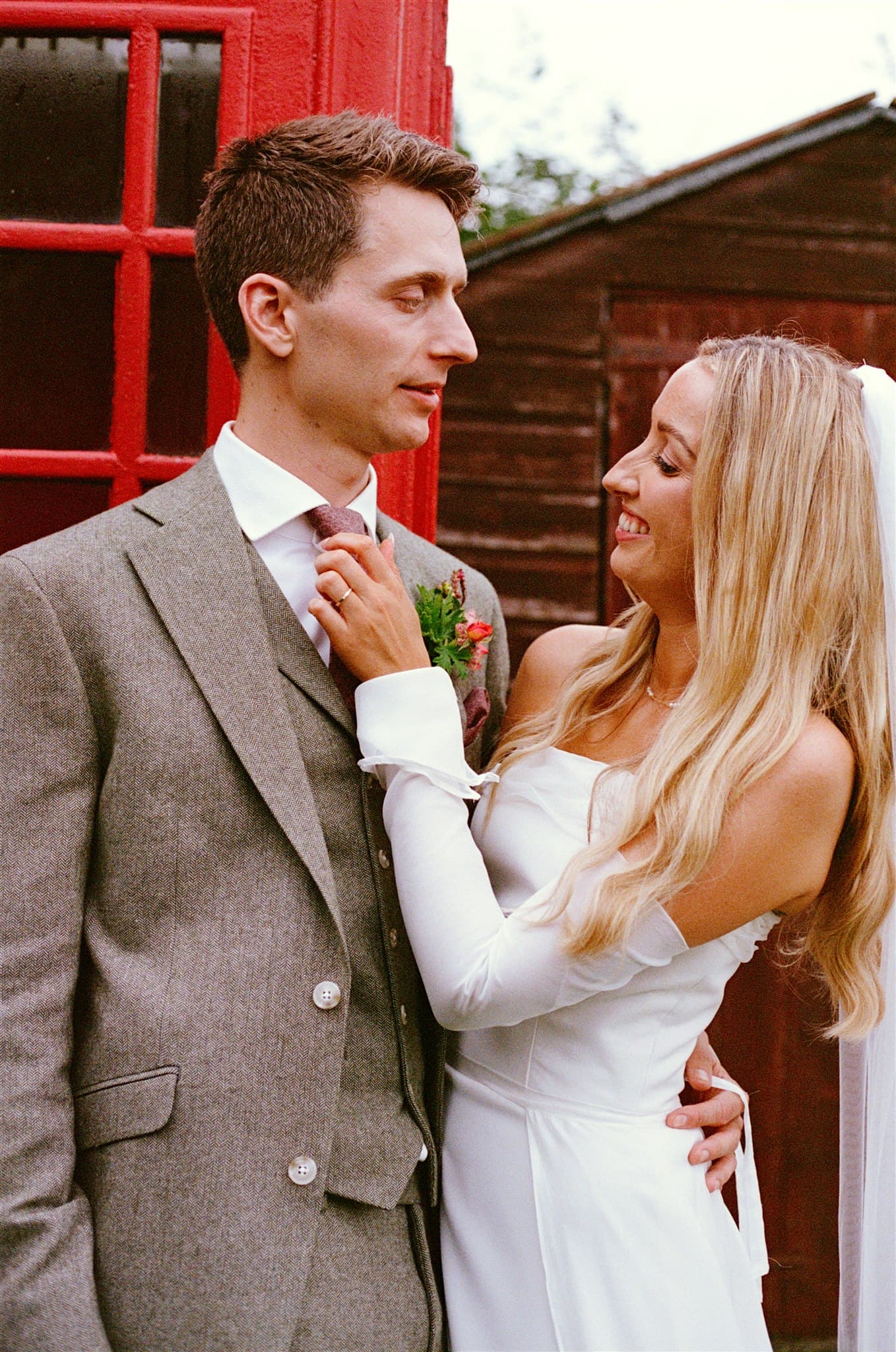 A film photo of Wedding couple standing close, bride adjusting groom's tie.