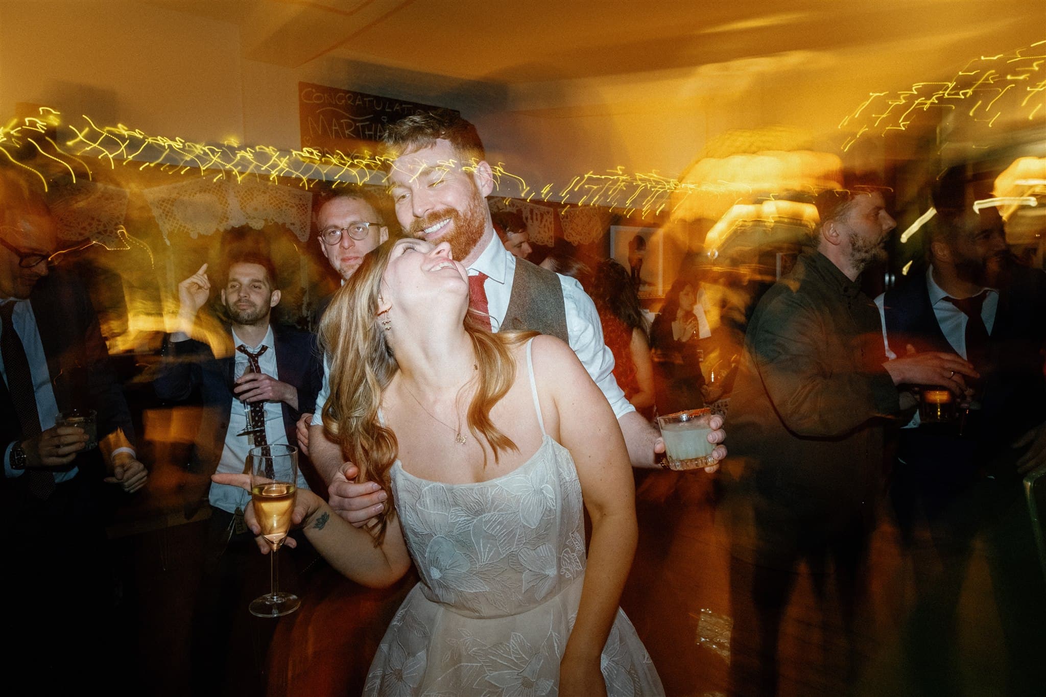 A bustling indoor party scene with guests holding drinks and motion blur effects.